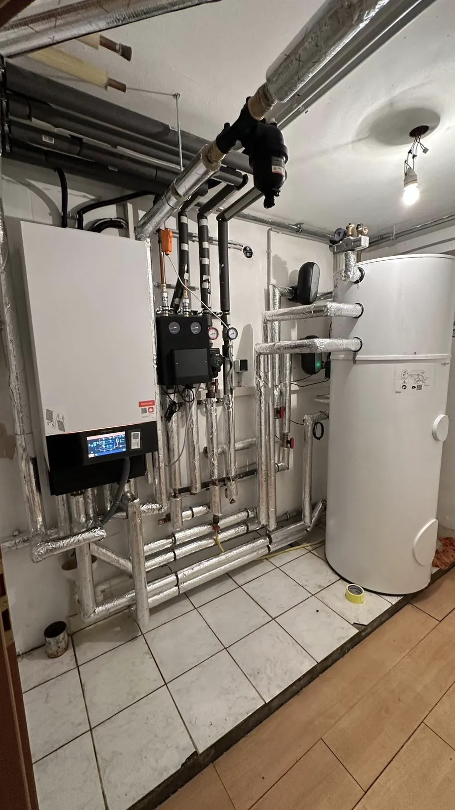Technikraum mit Wärmepumpen-Inneneinheit, Pumpengruppe und Warmwasserspeicher